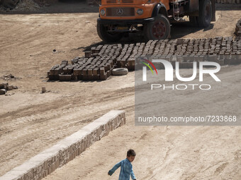 A young Afghan refugee boy plays with a plastic box in a brick factory, in the Borkhar area in the west of the city of Isfahan 439Km (273 Mi...