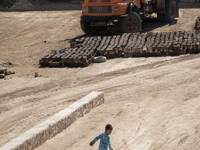 A young Afghan refugee boy plays with a plastic box in a brick factory, in the Borkhar area in the west of the city of Isfahan 439Km (273 Mi...