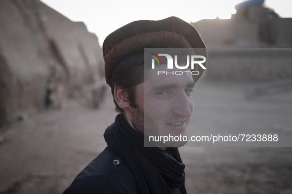 An Afghan refugee labor wearing Afghan traditional clothes smiles as he stands in a brick factory after a working day in the Borkhar area in...