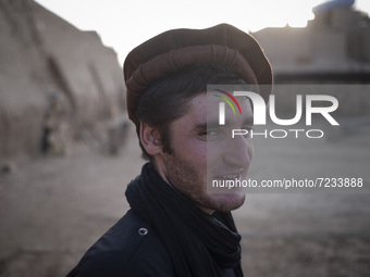 An Afghan refugee labor wearing Afghan traditional clothes smiles as he stands in a brick factory after a working day in the Borkhar area in...