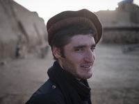 An Afghan refugee labor wearing Afghan traditional clothes smiles as he stands in a brick factory after a working day in the Borkhar area in...