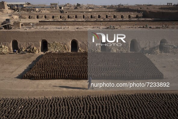 An Afghan refugee labor walks past newly bricks while working in a brick factory in the Borkhar area in the west of the city of Isfahan 439K...