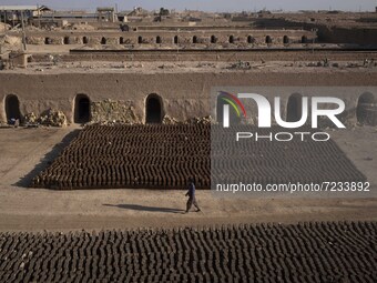 An Afghan refugee labor walks past newly bricks while working in a brick factory in the Borkhar area in the west of the city of Isfahan 439K...