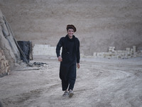 An Afghan refugee labor wearing Afghan traditional clothes smiles as he walks along an area in a brick factory after a working day in the Bo...