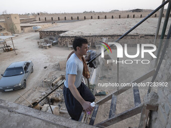 An Afghan refugee labor wearing clean clothes climbs stairs after taking shower in a brick factory after a working day in the Borkhar area i...