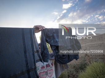 An Afghan refugee labor hangs his washed clothes from a rope out of his hut which is shared with five other Afghan laborers in a brick facto...