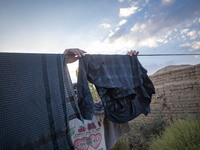 An Afghan refugee labor hangs his washed clothes from a rope out of his hut which is shared with five other Afghan laborers in a brick facto...