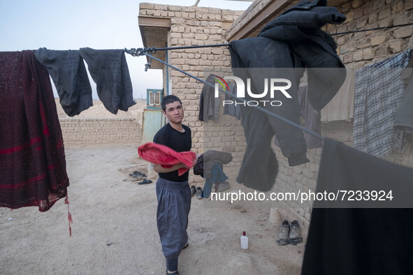 An Afghan refugee labor holds his washed clothes while standing in front of his hut which is shared with five other Afghan laborers in a bri...