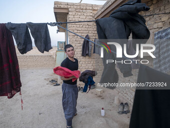 An Afghan refugee labor holds his washed clothes while standing in front of his hut which is shared with five other Afghan laborers in a bri...