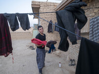 An Afghan refugee labor holds his washed clothes while standing in front of his hut which is shared with five other Afghan laborers in a bri...