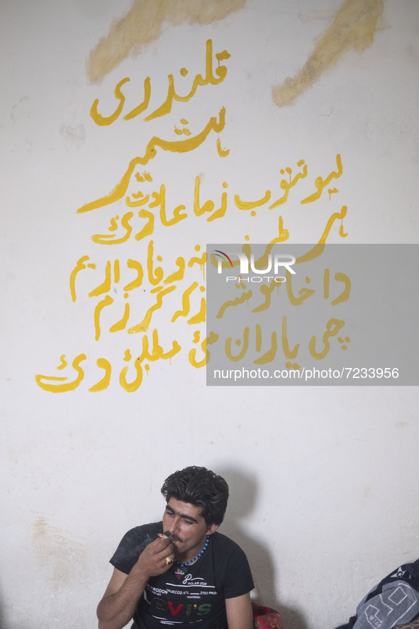 An Afghan refugee labor puffs on a cigarette as he sits at his hut which is shared with four other Afghan laborers in a brick factory after...