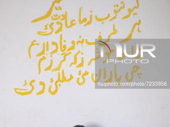 An Afghan refugee labor puffs on a cigarette as he sits at his hut which is shared with four other Afghan laborers in a brick factory after...