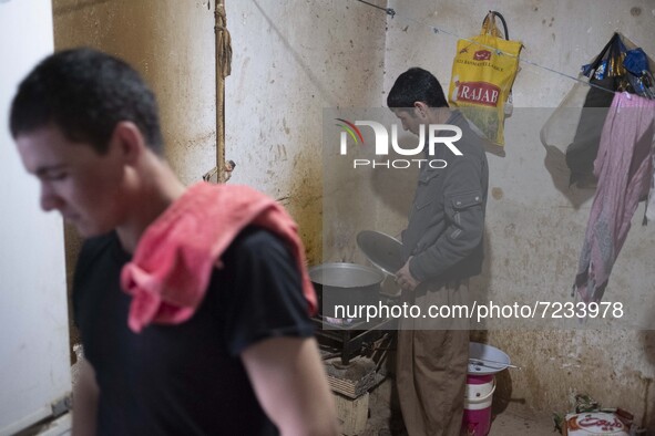 An Afghan refugee labor cooks meat for dinner after a working day in a brick factory in the Borkhar area in the west of the city of Isfahan...