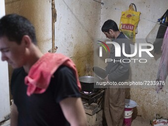 An Afghan refugee labor cooks meat for dinner after a working day in a brick factory in the Borkhar area in the west of the city of Isfahan...