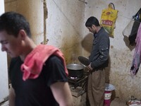 An Afghan refugee labor cooks meat for dinner after a working day in a brick factory in the Borkhar area in the west of the city of Isfahan...