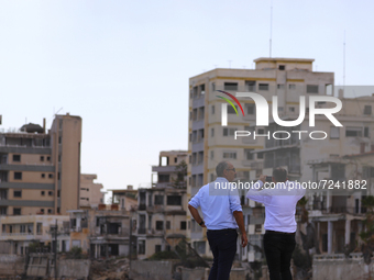 Men watch and photograph abandoned hotels on the beach, fenced off by the Turkish military since 1974, in the abandoned coastal area of Varo...