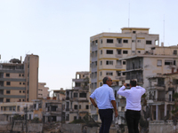 Men watch and photograph abandoned hotels on the beach, fenced off by the Turkish military since 1974, in the abandoned coastal area of Varo...