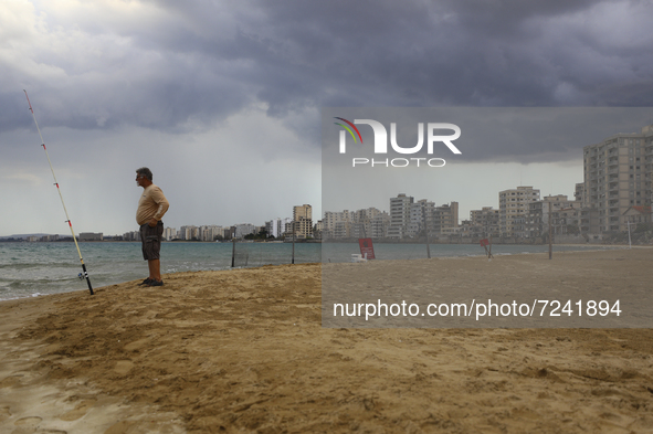 A man fishes on a beach in front of abandoned hotels fenced in by the Turkish military since 1974, in an abandoned coastal area of Varosha,...