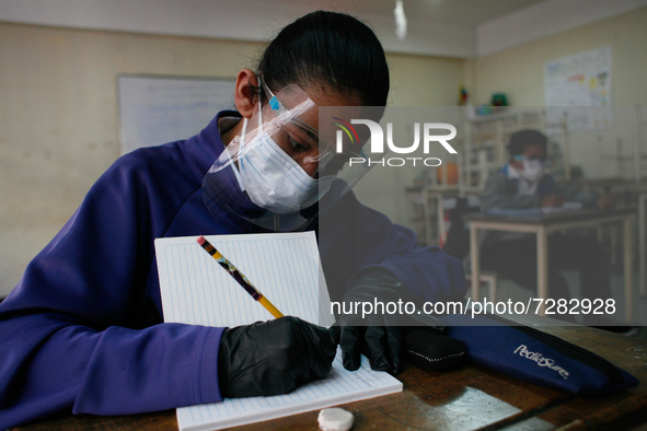 A girl copies in her notebook during the start of face-to-face classes at all levels amidst the Coronavirus pandemic in Caracas, Venezuela O...