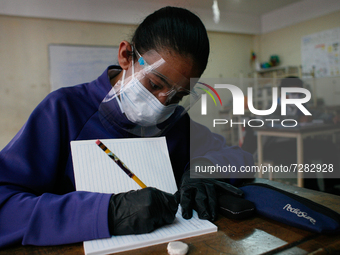 A girl copies in her notebook during the start of face-to-face classes at all levels amidst the Coronavirus pandemic in Caracas, Venezuela O...