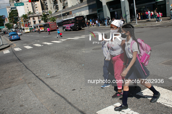 A woman walks with two children outside the school during the start of face-to-face classes at all levels amid the Coronavirus pandemic in C...