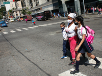 A woman walks with two children outside the school during the start of face-to-face classes at all levels amid the Coronavirus pandemic in C...