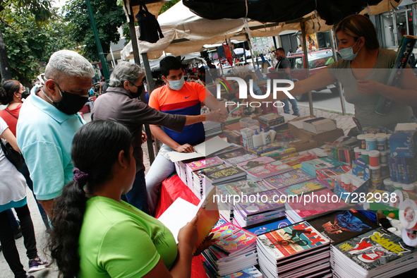 A vendor hands a pencil to a customer at a school fair in the midst of the Coronavirus pandemic in Caracas, Venezuela on October 25, 2021. 