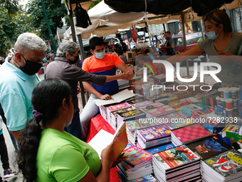 A vendor hands a pencil to a customer at a school fair in the midst of the Coronavirus pandemic in Caracas, Venezuela on October 25, 2021. (