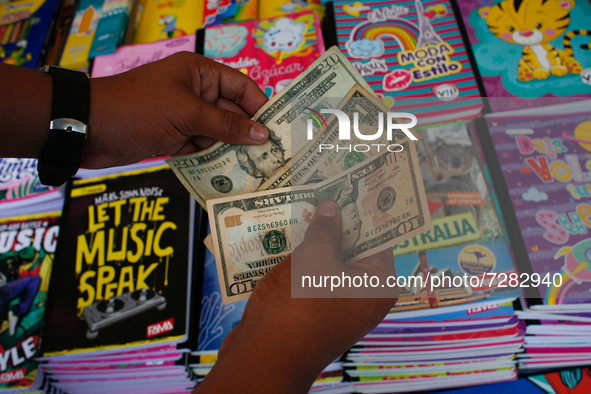 A school supplies vendor counts U.S. dollars after making a sale in the midst of the Coronavirus pandemic in Caracas, Venezuela October 25,...