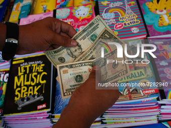 A school supplies vendor counts U.S. dollars after making a sale in the midst of the Coronavirus pandemic in Caracas, Venezuela October 25,...