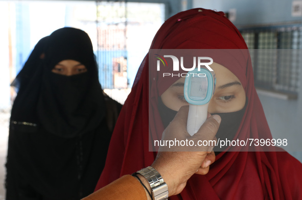 A staff checks the body temperature of a student at the entrance of School and maintain social distancing and covid protocol at the first da...