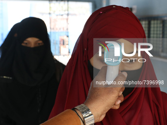 A staff checks the body temperature of a student at the entrance of School and maintain social distancing and covid protocol at the first da...