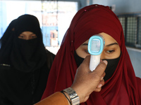 A staff checks the body temperature of a student at the entrance of School and maintain social distancing and covid protocol at the first da...