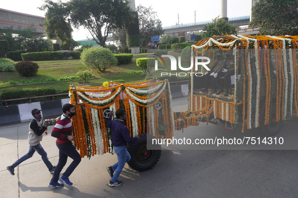 People participate as officials escort the vehicle covered with flowers carrying the casket of India's Chief of Defence Staff General Bipin...