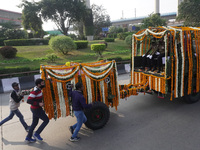 People participate as officials escort the vehicle covered with flowers carrying the casket of India's Chief of Defence Staff General Bipin...