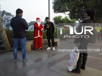 People click pictures with a man dressed as Santa Claus at a marketplace on the eve of Christmas, amidst the coronavirus (COVID-19) pandemic...