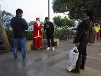 People click pictures with a man dressed as Santa Claus at a marketplace on the eve of Christmas, amidst the coronavirus (COVID-19) pandemic...