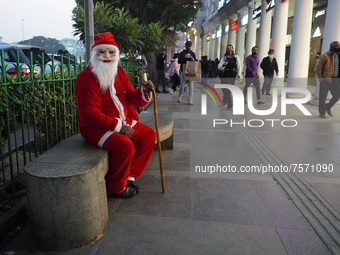 A man dressed as Santa Claus sits on a bench at a marketplace on the eve of Christmas, amidst the coronavirus (COVID-19) pandemic, in New De...