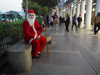 A man dressed as Santa Claus sits on a bench at a marketplace on the eve of Christmas, amidst the coronavirus (COVID-19) pandemic, in New De...