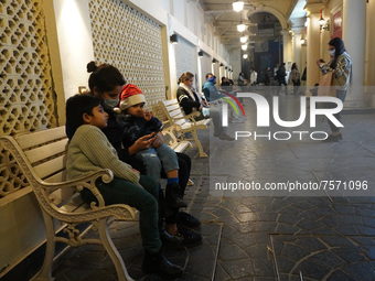 A girl wearing a Santa hat sits with her mother in a decorated alley on the eve of Christmas, amidst the coronavirus (COVID-19) pandemic, in...