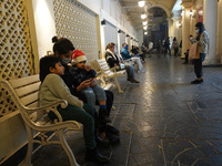 A girl wearing a Santa hat sits with her mother in a decorated alley on the eve of Christmas, amidst the coronavirus (COVID-19) pandemic, in...