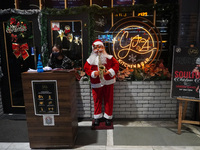 A woman talks on phone as she stands next to a Santa Claus installed outside a restaurant on the eve of Christmas, amidst the coronavirus (C...