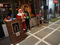 People click pictures next to a Santa Claus installed outside a restaurant on the eve of Christmas, amidst the coronavirus (COVID-19) pandem...