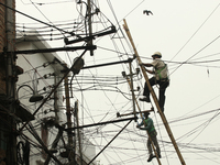 A worker hangs from an electric post while he repairs power lines in Kolkata on January 24,2022. (