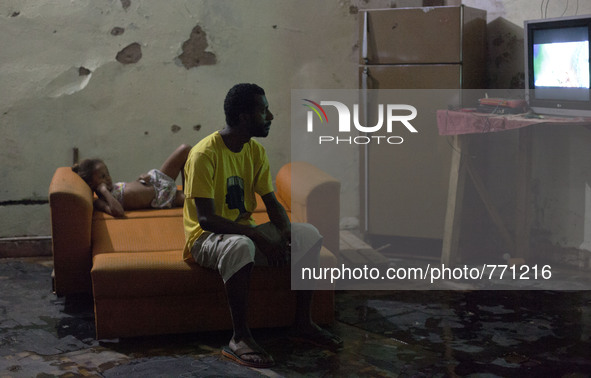 Clayton and one of the children in the occupation watch TV in a makeshift living room. 

 These families having been occupying buildings f...