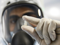 Laboratory technicians wearing full face masks and protective suits work to produce molnupiravir, the first tablet drug used to treat corona...