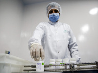 Laboratory technicians wearing full face masks and protective suits work to produce molnupiravir, the first tablet drug used to treat corona...