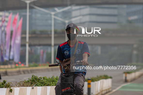 Man wear protective face masks rides bicycle in business district in Jakarta on February 14, 2022. The Minister of Manpower, Ida Fauziyah, s...