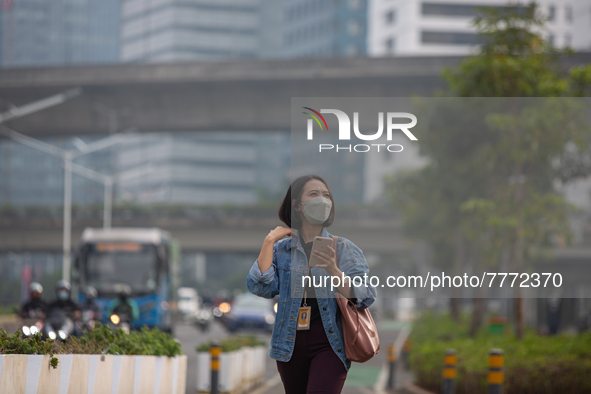 Woman wear protective face masks walk in business district in Jakarta on February 14, 2022. The Minister of Manpower, Ida Fauziyah, stipulat...