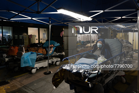 A patient lies in a hospital bed waiting for medical treatment in a temporary holding area outside Caritas Medical Center in Hong Kong, Chin...